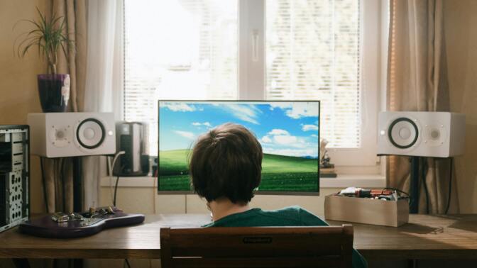 boy sitting in front of desktop computer with external speakers