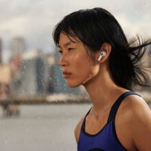 Sweaty person listening to airpod earbuds while looking into the distance with a city skyline in the background