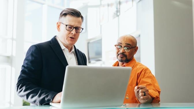 Two people looking at laptop screen and talking