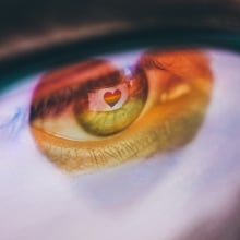 Woman with a rainbow heart reflected in her eyes and glasses.