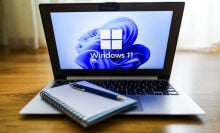 Microsoft Windows 11 laptop with notepad on keyboard