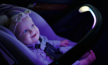 a baby looking at a sensorysoothe handle on an evenflo car seat