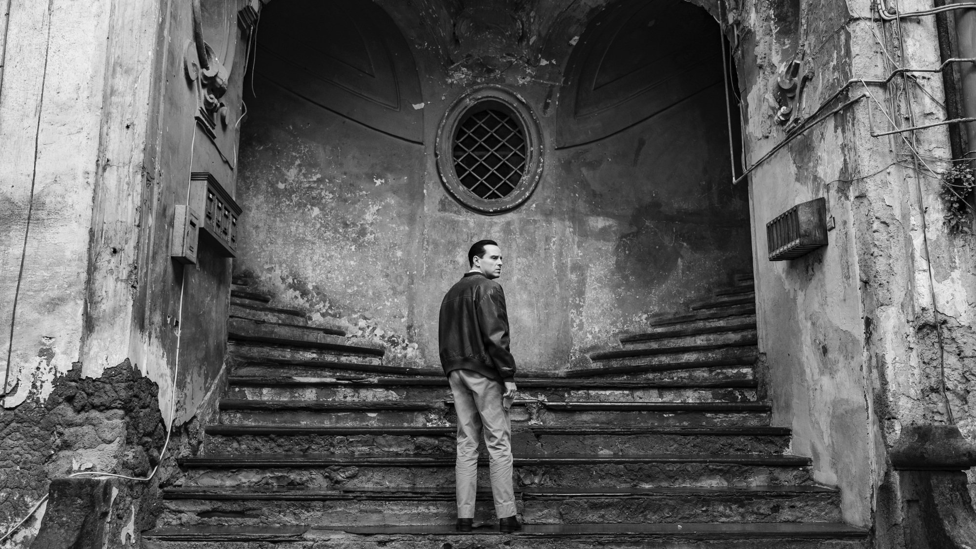 A man stands on a staircase to two different paths leading up.