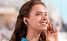 a person with long wavy hair looks into the distance while wearing the soundcore by anker p20i earbuds