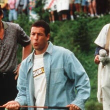 Adam Sandler and Chris McDonald stand on a golf course watching a play in the movie "Happy Gilmore"