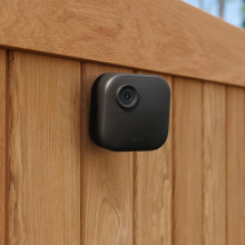 A Blink security camera on a wooden fence