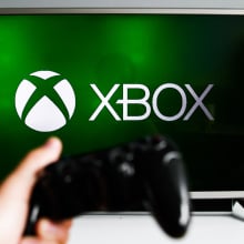 xbox logo on tv with hand holding controller in foreground