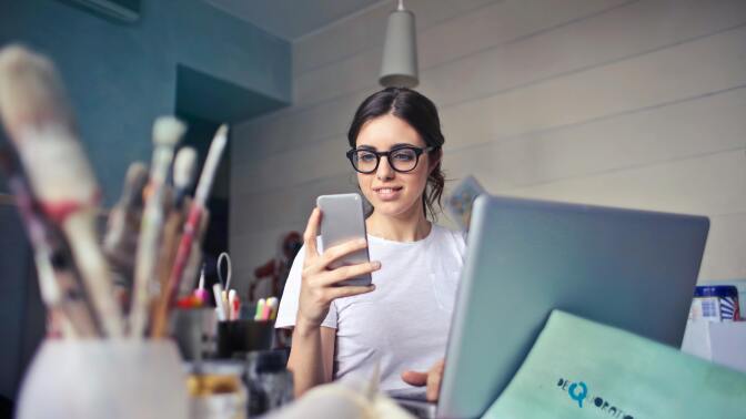 A woman looks at her phone at her workspace.