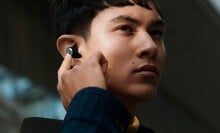 a person with the Sennheiser Momentum True Wireless 2 in their right ear with their right hand touching the earbud