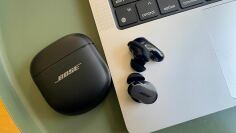 black bose qc ultra earbuds on table next to laptop