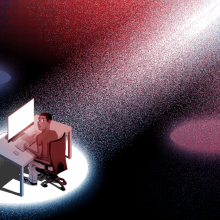 A spotlight shines on a man at his computer desk.