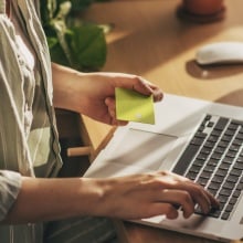 person sitting in front of laptop holding credit card