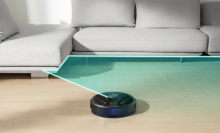 eufy robovac x8 hybrid vacuuming floor next to couch