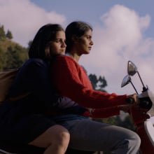 A mother and daughter ride together on a scooter.