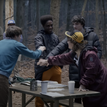 On set for "Stranger Things," four boys put their hands together.