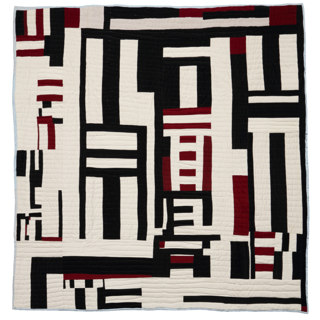 A quilt with an abstract design of rectangles and lines in black, white, and shades of red. The pattern is geometric and asymmetrical, creating a striking modern art appearance. The quilt features various widths and lengths of the shapes, arranged vertically and horizontally.