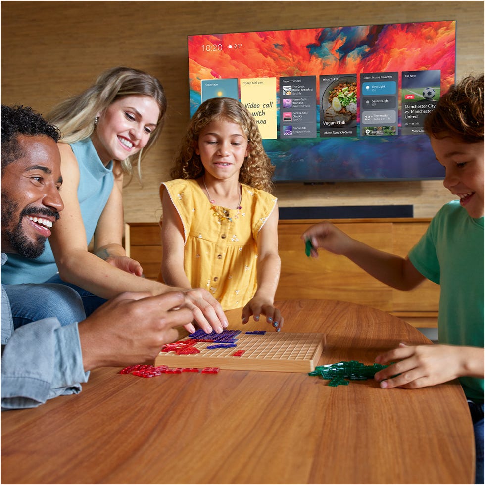 amazon fire tv omni qled on the wall behind a family playing games