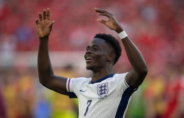 bukayo saka lifts his arms into the air and smiles with joy as he celebrates a goal for england