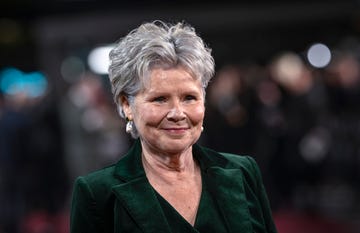 imelda staunton, wearing a green suit, smiles as she attends a red carpet event