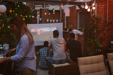 friends watching sports on big screen in backyard