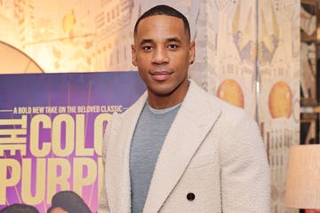 reggie yates at the color purple screening, wearing a grey jumper and a cream coat