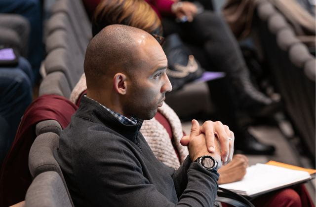 person sitting in audience intently watching and listening