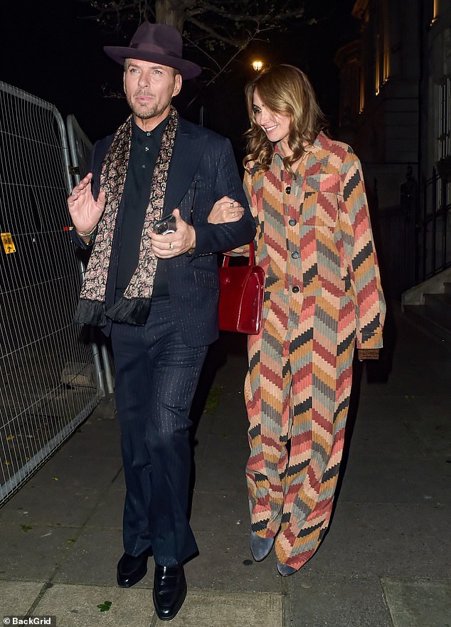 She looked stylish in a beige patterned jumpsuit and accessorised with a sleek red bag as she held his arm while departing the swanky venue