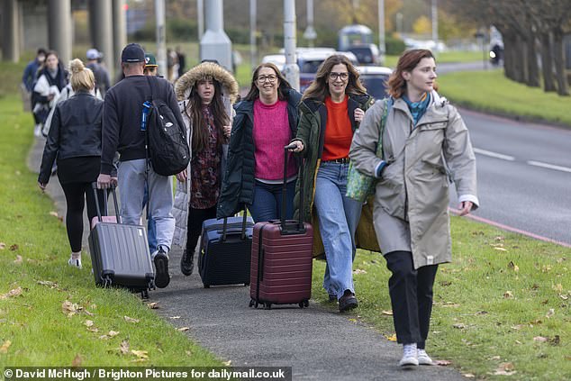 Passengers traipse along a footpath from the South Terminal at Gatwick to the North, where they hope for onward travel as the incident continues