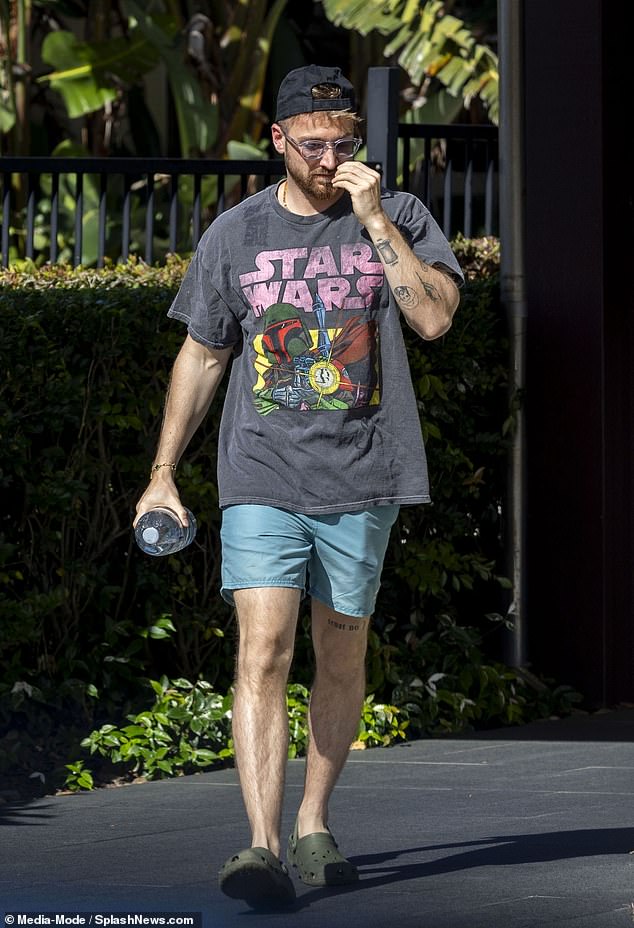 Sam rocked a backwards baseball cap and sunglasses as he arrived at the pool carrying a large bottle of water