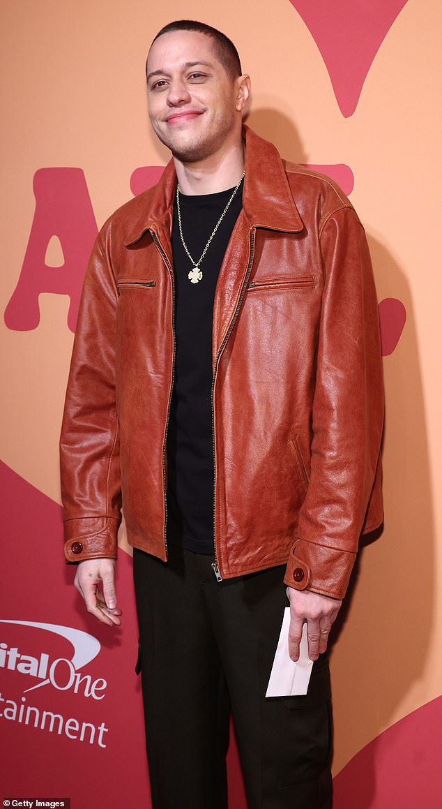 The star, whose famous dating roster includes Kim Kardashian and Ariana Grande, looked stylish in a black outfit topped with a burnt orange leather jacket