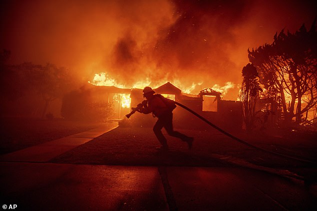 A firefighter battles the Palisades Fire as it burns a structure in the Pacific Palisades neighborhood of Los Angeles