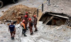 Aerial photo of the sinkhole with a pile of excavated rubble next to it and firefighters standing beside it