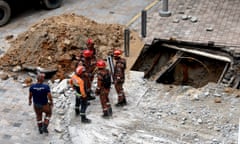 Malaysia fire and rescue officers stand near to a sinkhole and piles of debris in Kuala Lumpur.