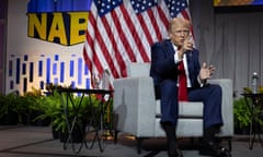 man in a suit sits on an armchair on a stage