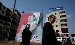 People walk in front of a billboard of the Syrian president, Bashar al-Assad, in Syria.