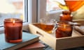 Burning candle on stack of books near window indoors, while tea is poured