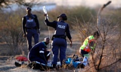 A paramedic receives help from a South African police officer as he tends to protesting mineworkers in Marikana, August 2012.