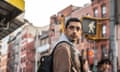 A man wearing a brown jacket and black backpack in New York City turns around