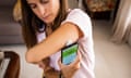 Woman monitoring herself the levels of glucose in blood using smart phone technology.<br>Continuous Glucose Monitoring (CGM) system with sensor attached in arm controlling information and alerts with mobile phone app.