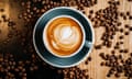 Black cup of coffee on the black and brown table among spilled roasted coffee beans.