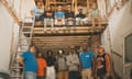 Thirteen workers stand and sit in a gutted building.