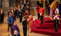 People walking past coffin in Westminster Hall, which is flanked by Beefeaters, soldiers and police officers.