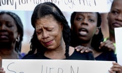 Woman cries as she holds placard with 'say her name' on front