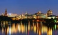 city at night over river with historical architecture.