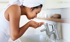 My skin care routine<br>Posed by model Shot of a young woman washing her face at the bathroom sink