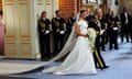 Crown Princess Victoria of Sweden in a wedding dress with a long trail, shoulders exposed, smiles as she walks into a church with her father, king Carl Gustaf