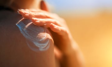 Woman applying sunblock cream on her shoulder.