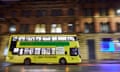 Yellow-and-black Bee Network bus drives through Manchester at night