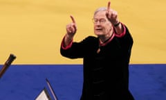 Man with index fingers raised in air in front of yellow/blue background