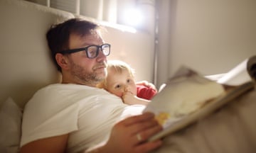 Father reading bedtime stories to child. Dad putting son to sleep. Quality family time. Parent reading book to child